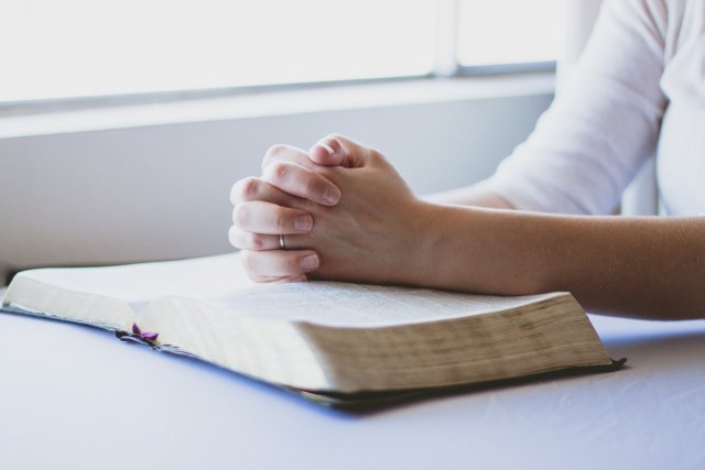prayer-1308663_1920-1 A Glorious Moment | Woman sitting with hands folded in prayer over a Bible